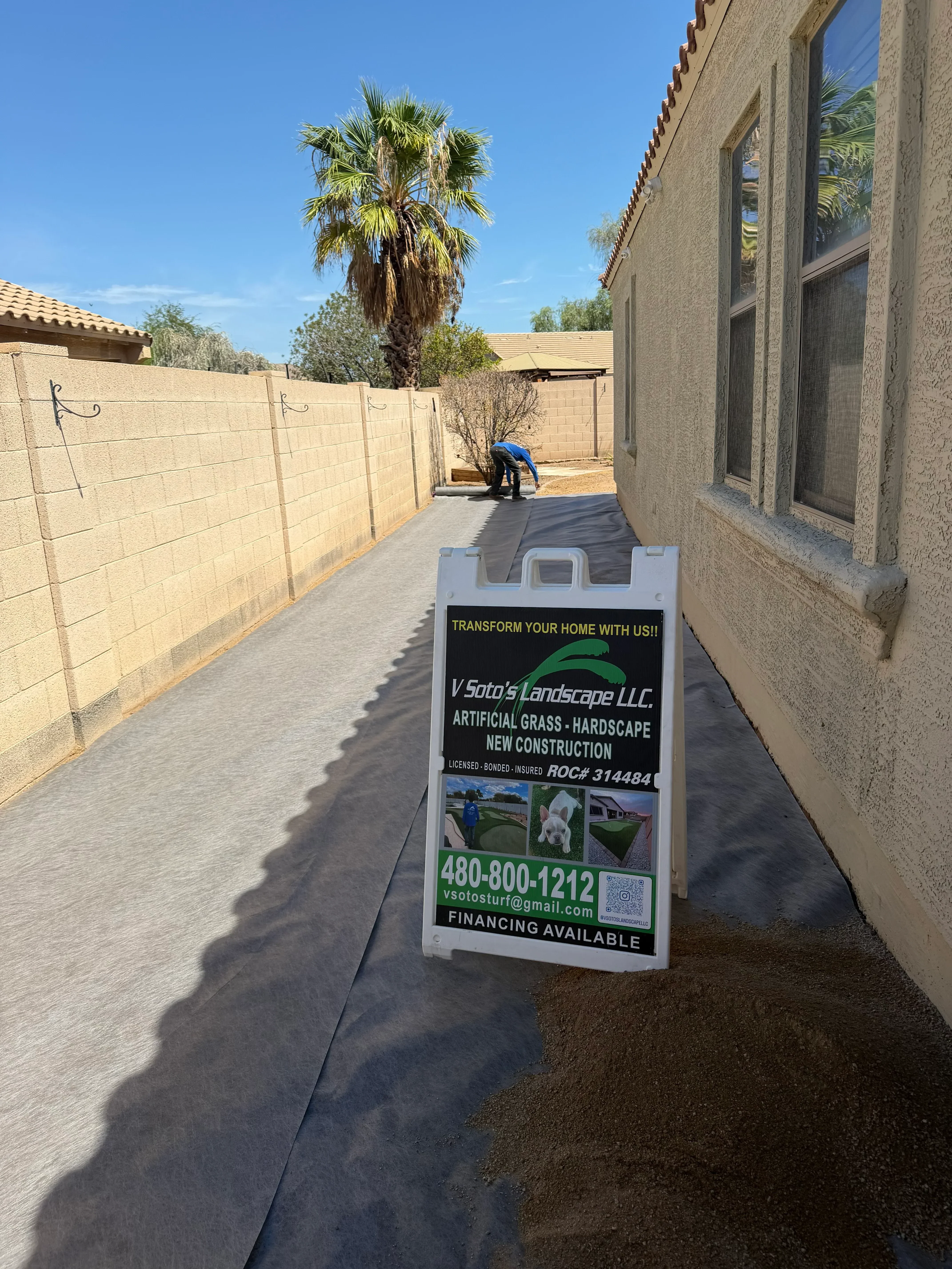 Concrete driveway with new sod, palm trees, and stucco home exterior