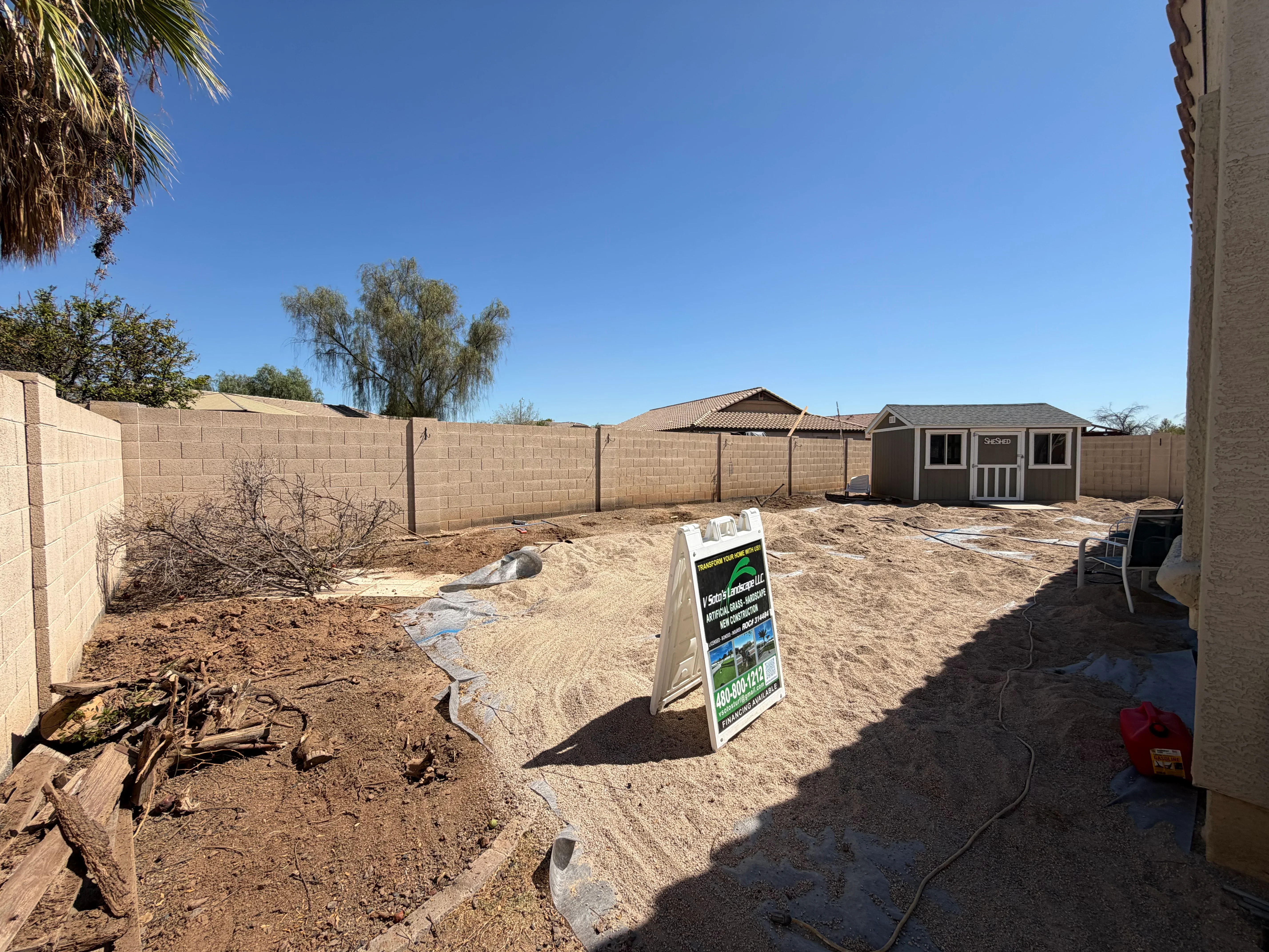 Graded backyard with concrete block walls, sandy soil, and storage shed ready for landscaping