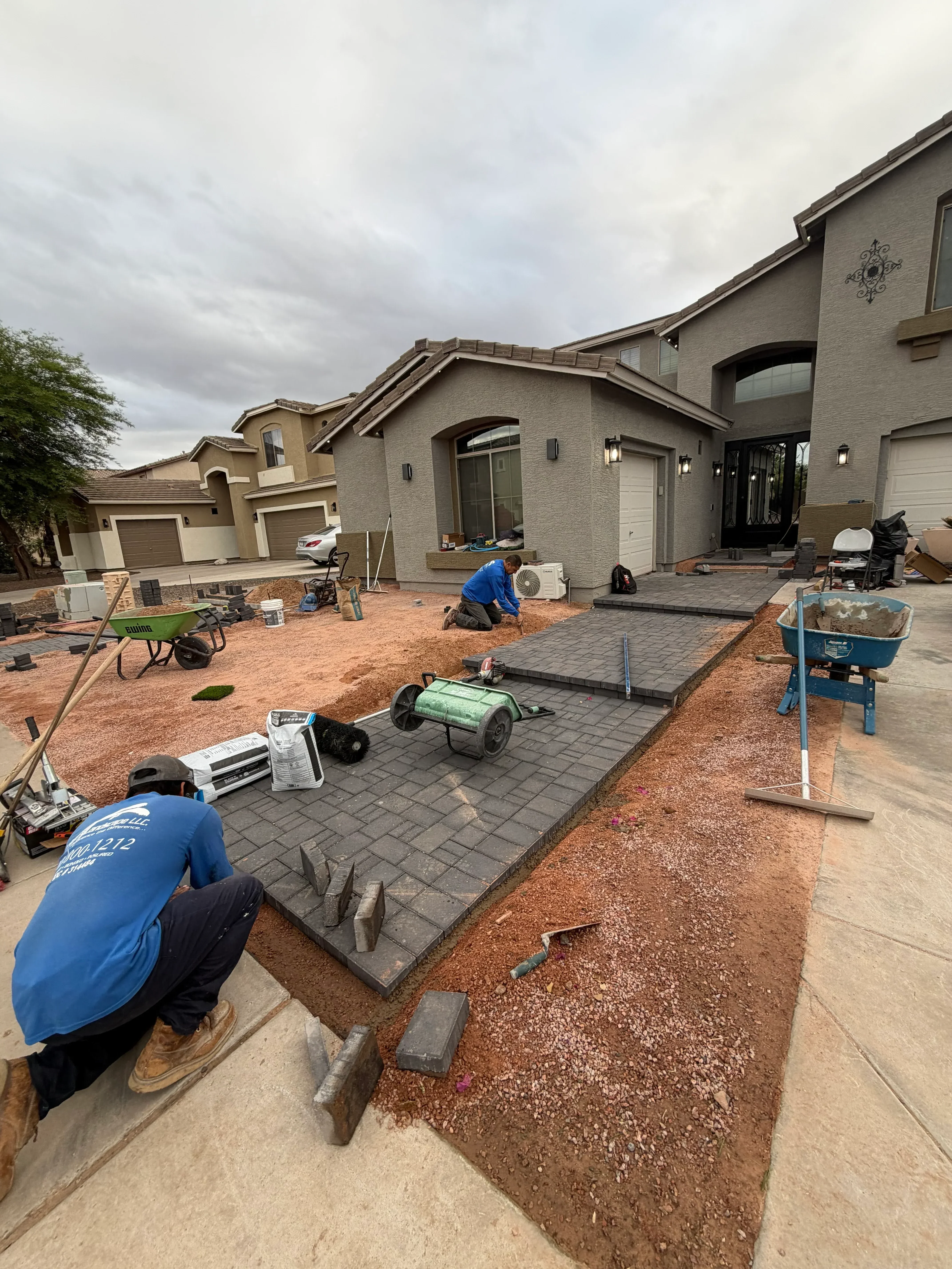 Residential yard with fresh topsoil, grading work, and mulch bed installation near brick home foundation