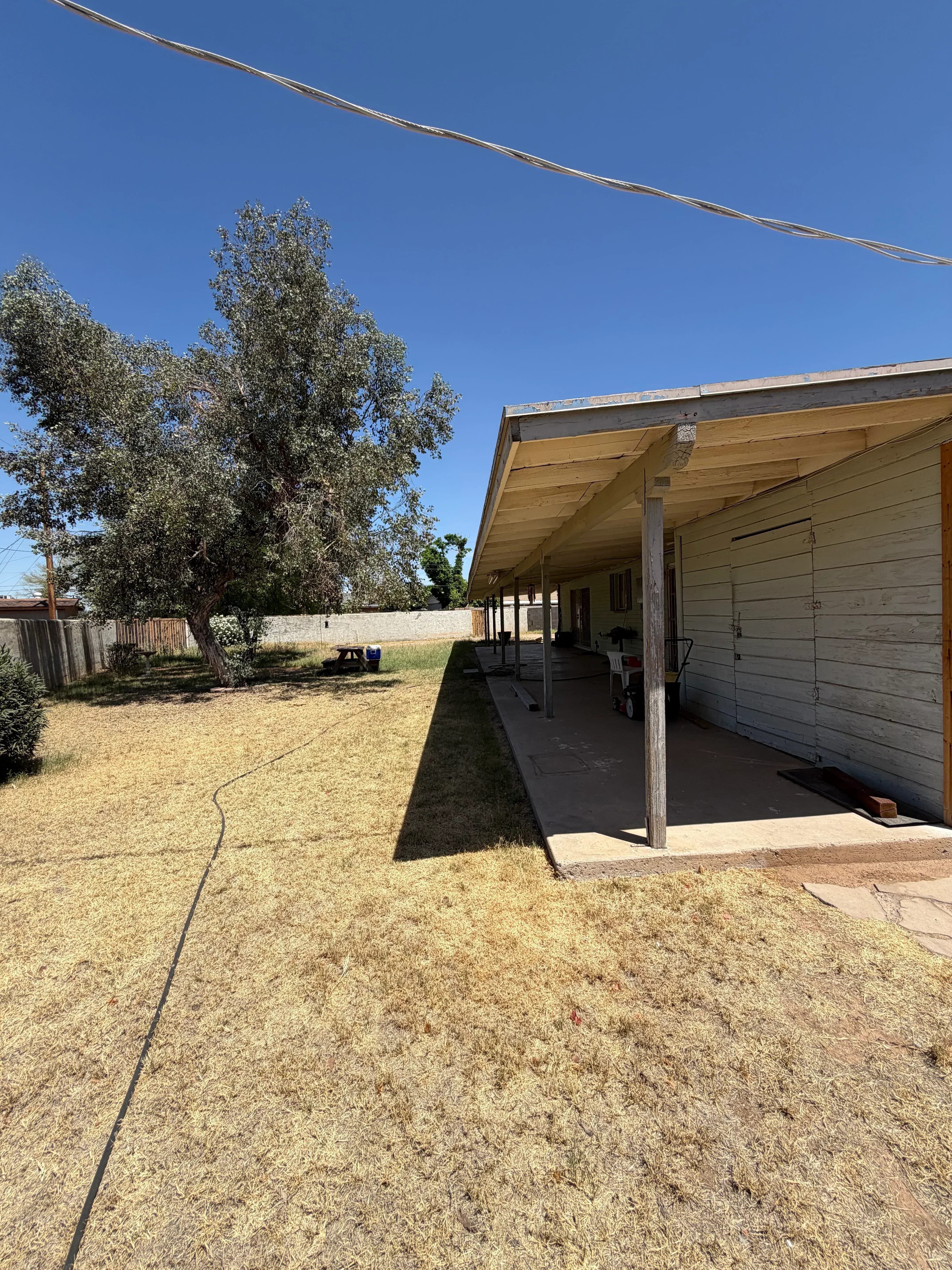Residential property with mature tree, maintained lawn, and stone foundation walls