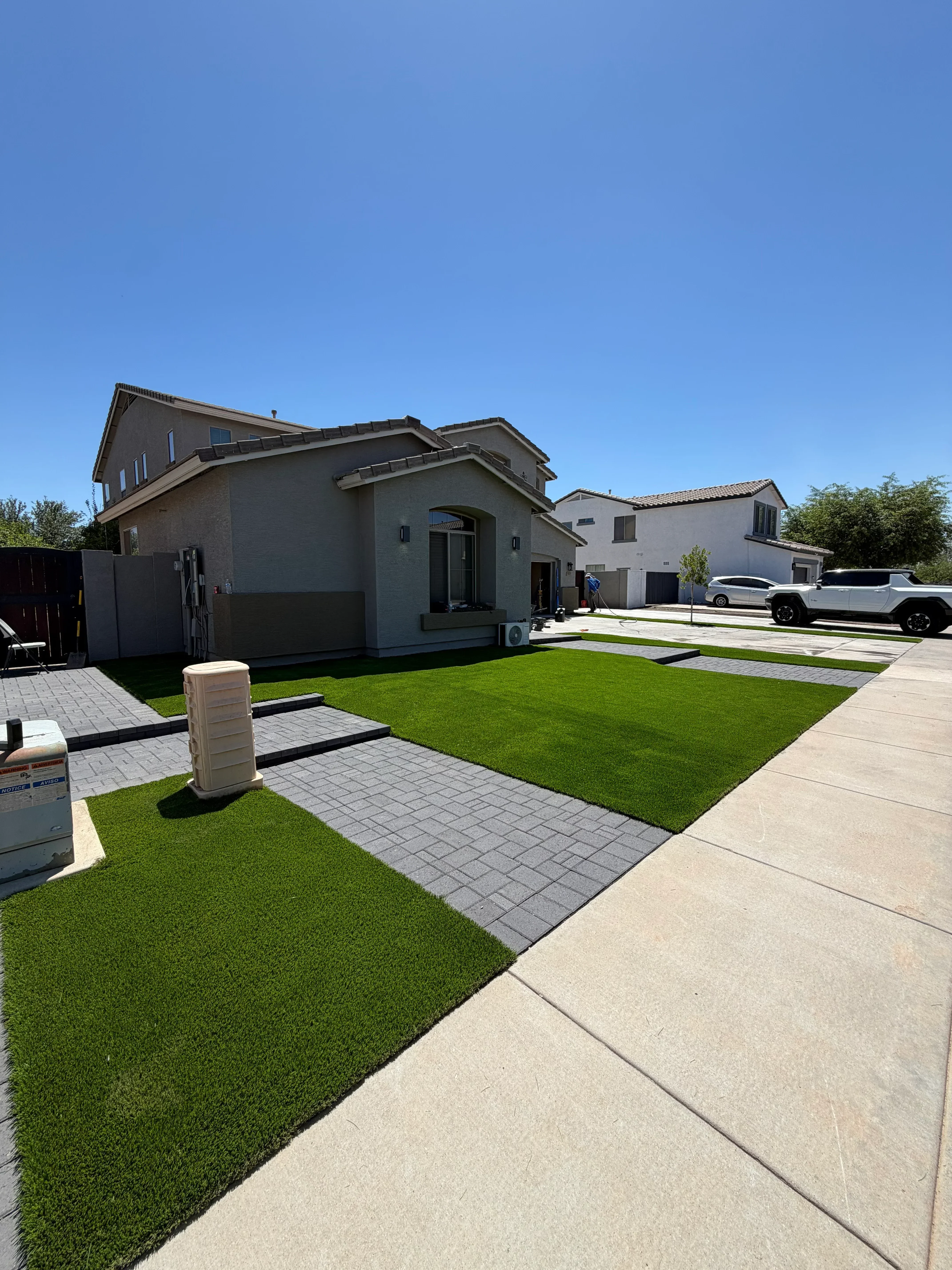 Newly installed sod lawn with paver patio and brick veneer foundation work
