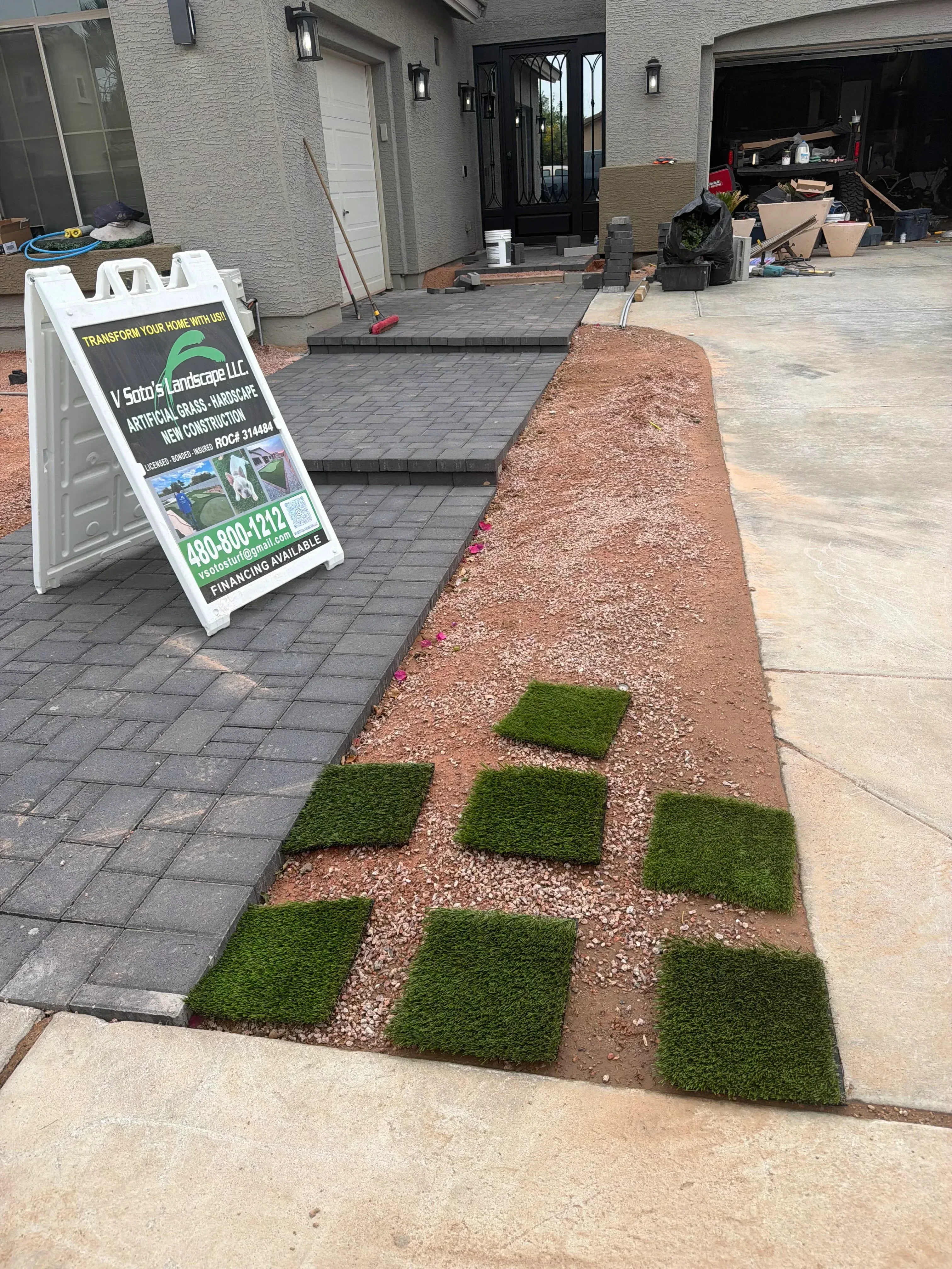 Red rock mulch and artificial turf squares with dark retaining wall in geometric pattern
